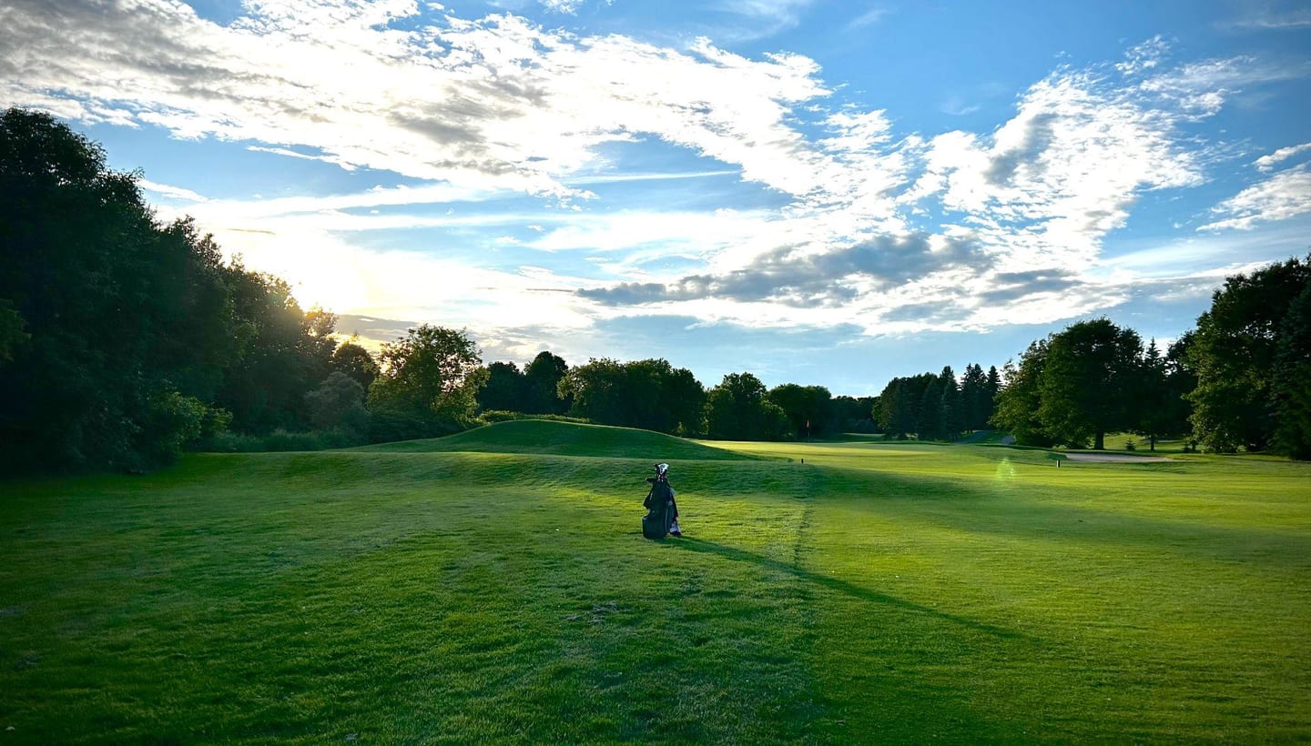 Allée de golf sous un ciel bleu, avec un sac au centre