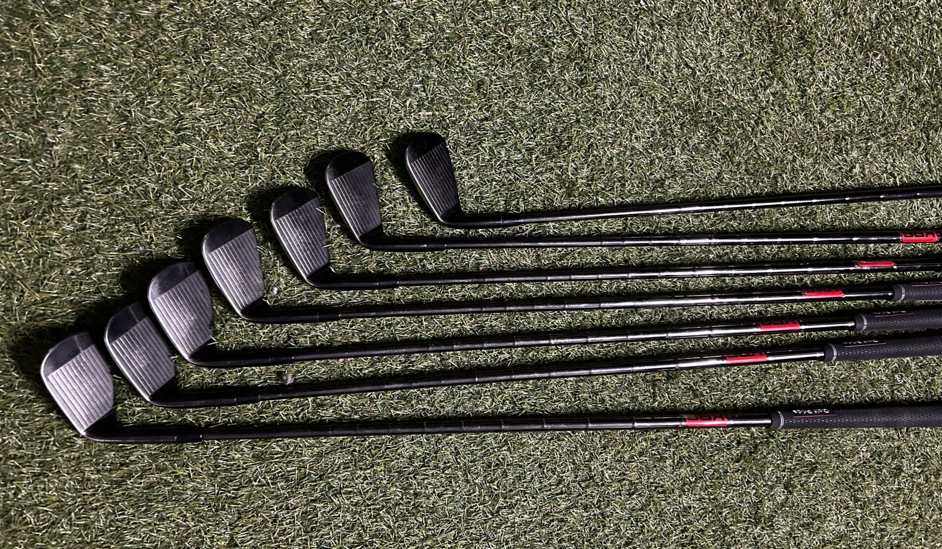 Fers Titleist AP2 718 à finition noire alignés sur le gazon.